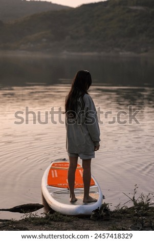 Young beautiful girl on a SUP board at sunset.