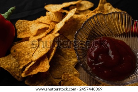 spicy triangular crisps scattered in the crate with red coloured ketchup. together a nice picture