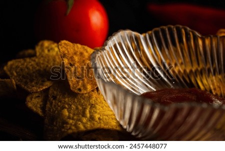 spicy triangular crisps scattered in the crate with red coloured ketchup. together a nice picture