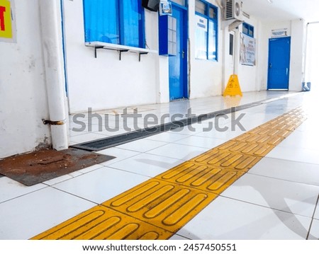 Yellow disabled friendly sidewalks between white tiles inside the public building