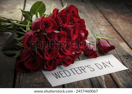 Red roses bouquet and white paper sheet for text on old rustic wooden table