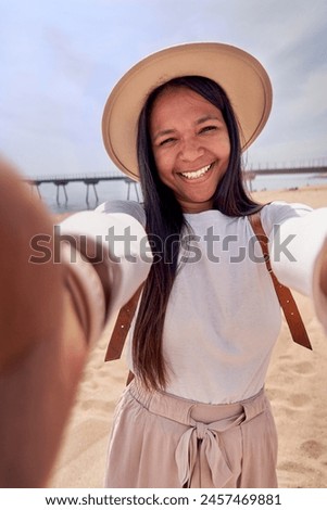 Cheerful African American woman using phone to take a vertical selfie at the beach capturing her summer holidays. Copy space image for social media apps.