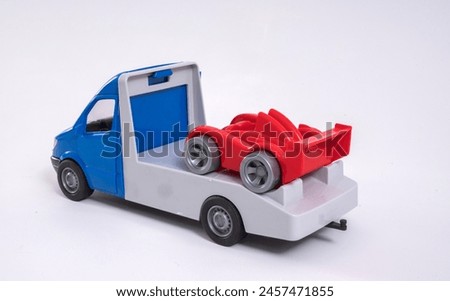 Multi-colored toy plastic tow truck with a red racing car on a white background.