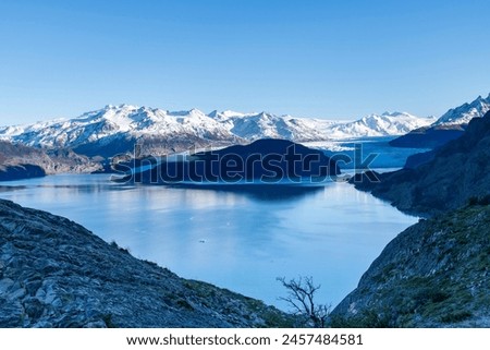Early morning panoramic view over Lago Grey lake and terminus of Glacier Grey in Torres del Paine National Park, Chile with first light of sunrise on snow covered mountains along the glacier Royalty-Free Stock Photo #2457484581
