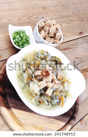 hot fresh diet vegetable soup with rye bread crackers over wood table on stand