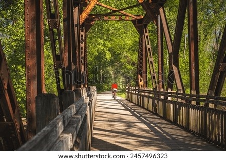 View from inside of railroad bridge  converted into recreational trail in summer; male bicyclist riding   in background