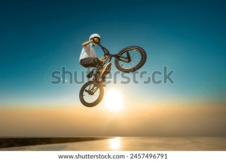 A teenager BMX Racing Rider performs tricks in a skate park on a pump track.