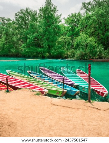 Six colorful wooden boats parked on the bank of a beautiful Huasteca river in El Esalto del Meco Mexico, with the tropical forest in the background