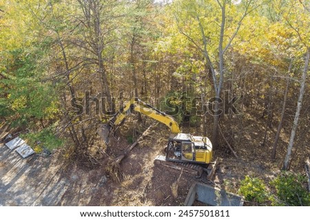 To prepare land for construction, trees were uprooted with an excavator tractor in order to make room for home Royalty-Free Stock Photo #2457501811