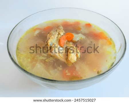 Close up view of chicken soup in a transparent bowl on a white background