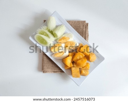top view of healthy food (cucumber, boiled egg and boiled sweet potato) on white plate on white background