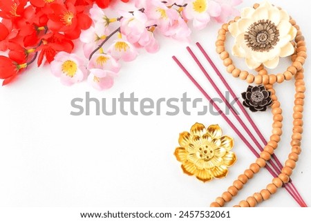 Isolated Empty white background decorated with colorful flowers, red colored incense and prayer beads. Concept for Vesak Day and Enlightenment Day. Empty blank copy text space