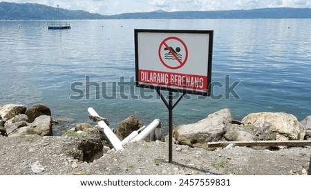 No swimming sign in front of lake, warning sign no swimming.