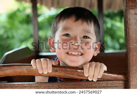 Malaysia - 02 16 2011 : Exterior photo view of handsome cute adorable good looking kid child children eurasian asian chinese boys sitting posing in a wooden carriage wood cart display happy smile joy