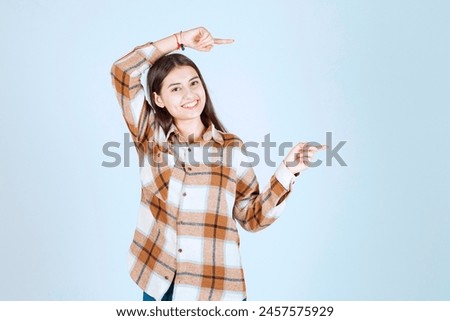 Photo of a young girl model standing and pointing away on white-gray background. High quality photo