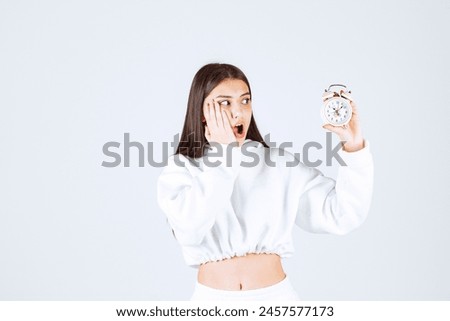 Picture of a cute young girl model holding an alarm clock. High quality photo