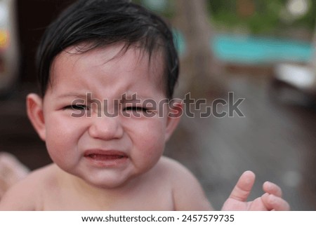Exterior photo portrait view of a grumpy unhappy sad crying moody baby kid child children eurasian asian chinese cute adorable kid children sitting alone 1 years old face expression toddler