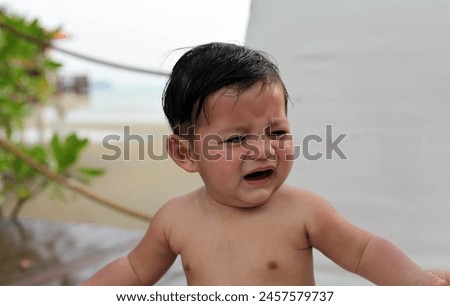Exterior photo portrait view of a grumpy unhappy sad crying moody baby kid child children eurasian asian chinese cute adorable kid children sitting alone 1 years old face expression toddler