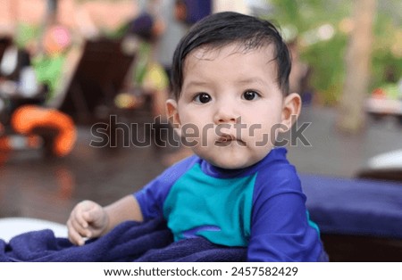 Malaysia - 02 13 2011 : Exterior photo portrait visual view of a handsome cute adorable good looking kid child children eurasian asian chinese boy baby at a resort hotel on long chair confused face