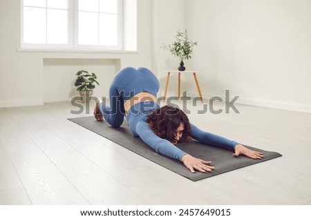 Beautiful sporty girl practices backbend yoga posture doing exercise for flexible spine and shoulders, fitness. Working out at home, white studio for good body shape, healthy lifestyle, training Royalty-Free Stock Photo #2457649015