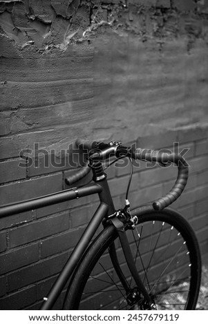 Black bicycle leaning against a brick wall. Sport wallpaper. Dark background Royalty-Free Stock Photo #2457679119