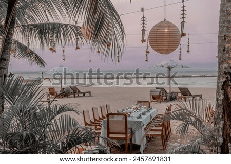 The dining table is neatly arranged and beautiful on the beach. surrounded by coconut trees and the evening sky which makes the atmosphere even more comfortable, you can also see umbrellas