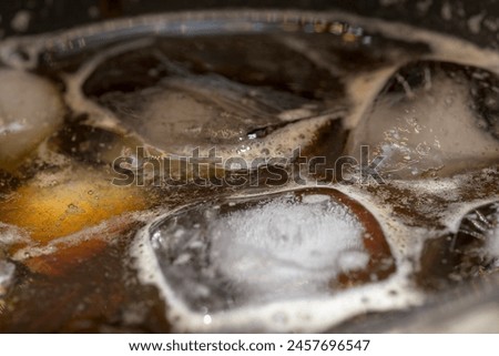 Ice cold black coffee with foam and bubbles macro photography in flat