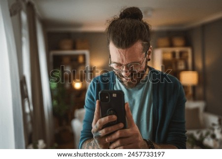 One adult caucasian man take a picture with mobile phone tattoos of himself at home