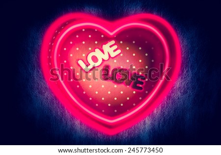 Heart-shaped gift box and two text "LOVE" middle box with double magic heart-shape neon or fluorescent light lines on dark background low key lighting picture style for a Valentine's day, love concept