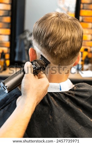 a blond child is in the barbershop and is being cut by a professional, the child is very happy and with blue eyes and freckles.