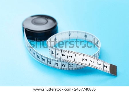 Tape measure on a blue background. Royalty-Free Stock Photo #2457740885