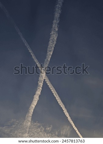 Contrail  the dark blue sky, the beautiful show forms the letter X Royalty-Free Stock Photo #2457813763