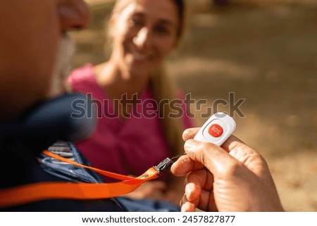 Close-up view of a caregiver's hand holding an SOS button offered to an elderly man, focused on safety and assistance Royalty-Free Stock Photo #2457827877