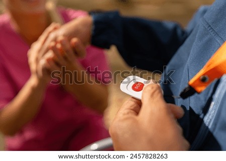 Close-up of an elderly man's hand with a caregiver, focusing on a red SOS button for emergencies Royalty-Free Stock Photo #2457828263