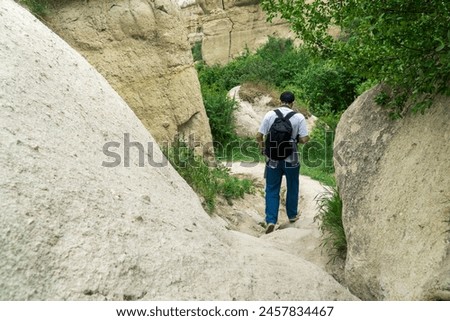 The male model is going down a narrow pathway in Cappadocia Pigeon Valley.