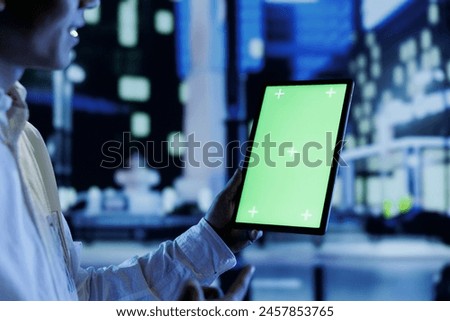 Man having fun walking around city at night, scrolling on online shopping platform using green screen tablet, close up. Citizen using chroma key device while strolling on empty streets
