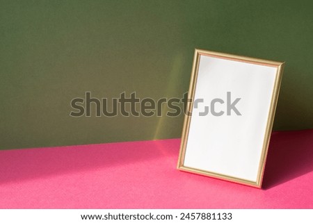 Gold picture frame with copy space on pink table. khaki green wall background