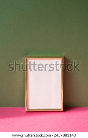 Gold picture frame with copy space on pink table. khaki green wall background