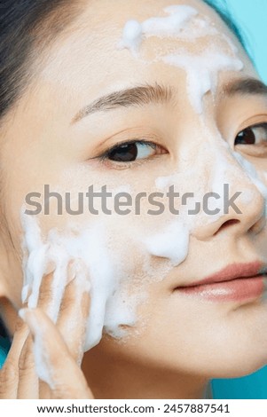 Young Asian woman and cosmetic textures photographed against a blue background