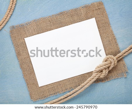 Blank paper card with ship rope over blue wooden background