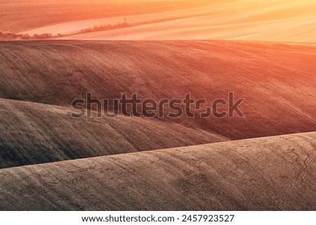 Almost like an abstract painting painted by nature itself - the undulating and plowed fields of Moravian Tuscany in southern Moravia in the glow of the setting sun in warm autumn tones Royalty-Free Stock Photo #2457923527