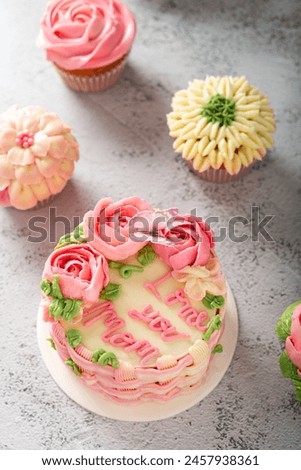 Mothers Day celebration cake with Love you Mom text, next to colorful cupcakes.