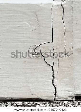 a photography of a fire hydrant is shown with a crack in the wall.