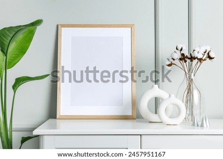 Mockup photo frame on the white wooden cabinet with house plants. Blank picture frame template on a wall. Modern scandinavian style interior