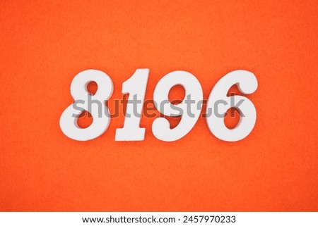 The number 8196 is made from white painted wood placed on a background of orange paper.
