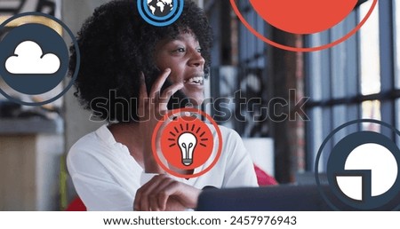Image of icon in circles over biracial woman laughing and talking on cellphone. Digital composite, globalization, cloud computing, ideas, message, communication and technology concept. Royalty-Free Stock Photo #2457976943