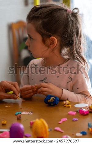 Tender image of mother and daughter enjoying games at home. The concentrated girl, the participatory mother, creating emotional bonds on a cozy afternoon. Royalty-Free Stock Photo #2457978597