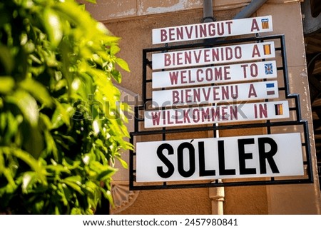 At Sóller train station, a welcome sign in five languages (Catalan, Spanish, English, French, German) invites tourists to explore the charming town of Sóller in the idyllic landscapes of Mallorca.
