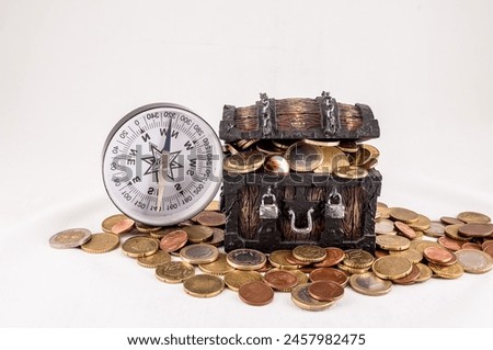 A treasure chest full of coins and a compass. The compass is pointing to the right, real image