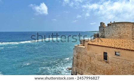 Photo of the Maniace Castle in Syracuse, Sicily Italy, a 13th century military fortress overlooking the sea with impressive stone walls, circular towers and views.